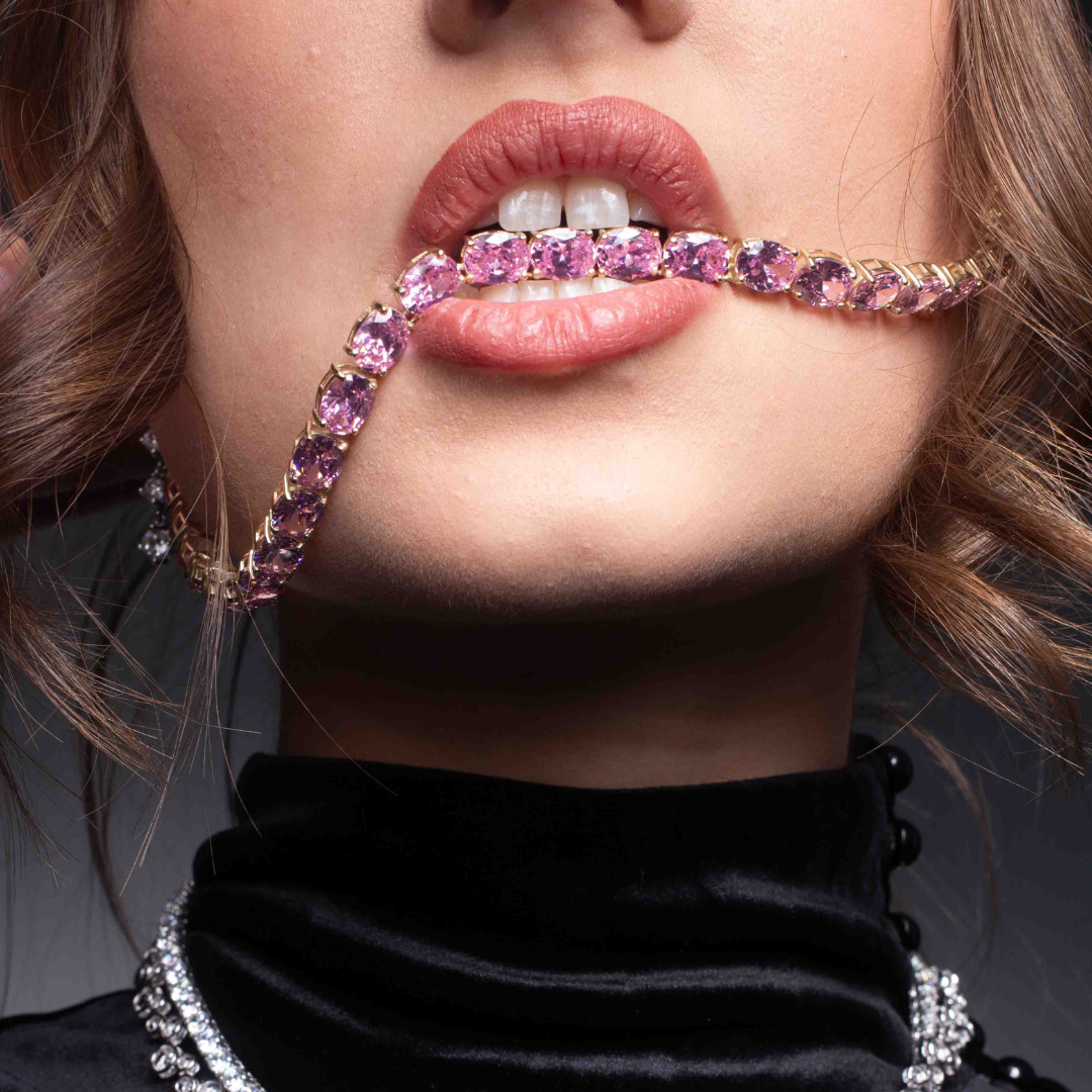 Close-up of a person wearing a pink gemstone necklace with a black garment.